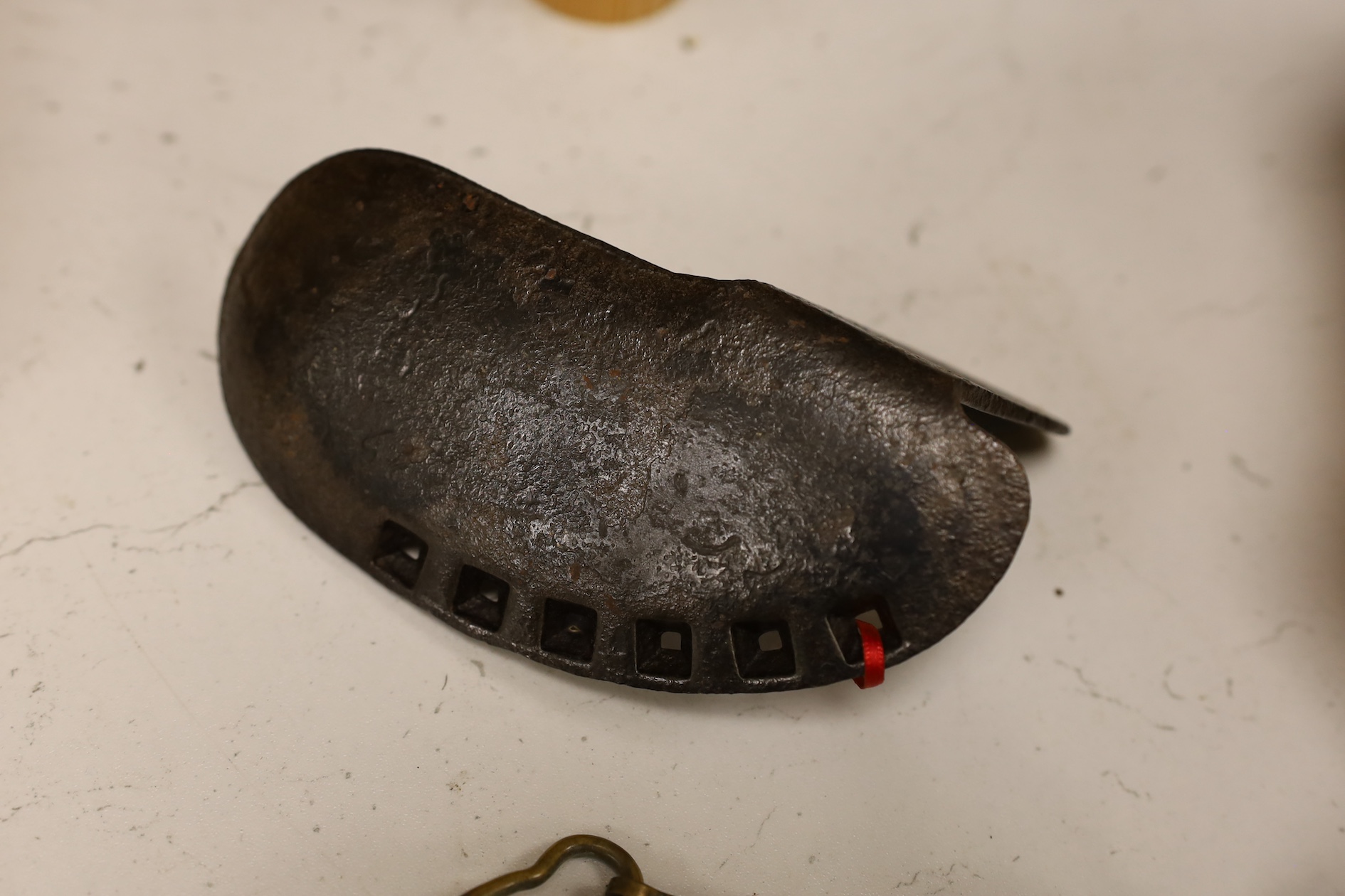 A cast iron toy model of a tricycle, a carved wooden bow, a classical figurative door knocker, a pair of metal cow shoes and two ceramic cistern pulls, bowl 30cm diameter. Condition - fair